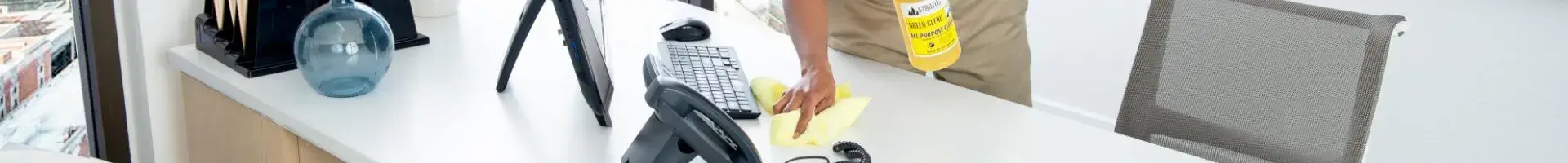 A Stratus Franchisee Cleaning a Large Office Desk and Computer in a High Rise Building