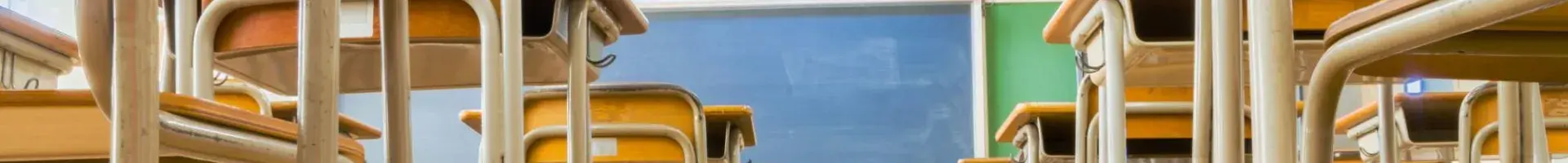 Inside a Clean School Room with Desks and a Blackboard in the Background