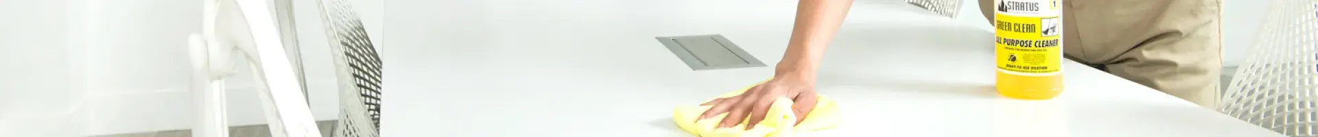 Stratus Franchisee Wiping Down an Office Desk Using a Yellow Cleaning Cloth
